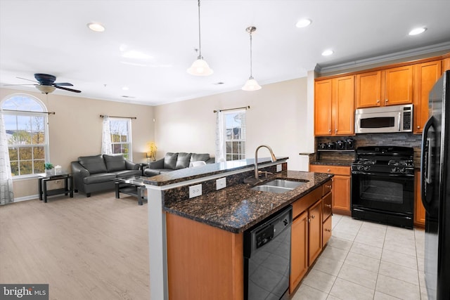kitchen with a sink, tasteful backsplash, open floor plan, ceiling fan, and black appliances