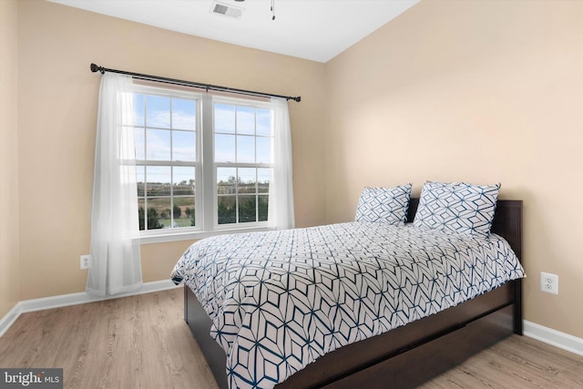 bedroom with baseboards, wood finished floors, and visible vents