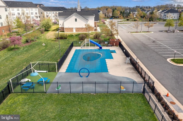 view of pool featuring a lawn, fence, and a residential view