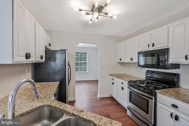 11620 Myrtle Oak Ct, Waldorf, MD 20601 - kitchen with black microwave, gas stove, arched walkways, freestanding refrigerator, and white cabinets
