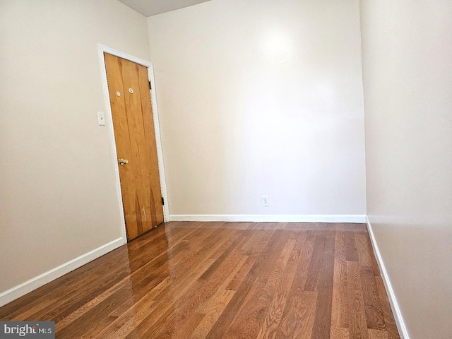 spare room featuring baseboards and wood finished floors