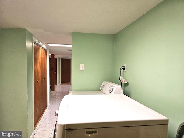 laundry room featuring washing machine and clothes dryer, light tile patterned flooring, and laundry area