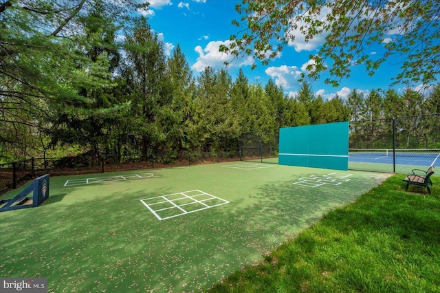 view of property's community featuring fence and a tennis court