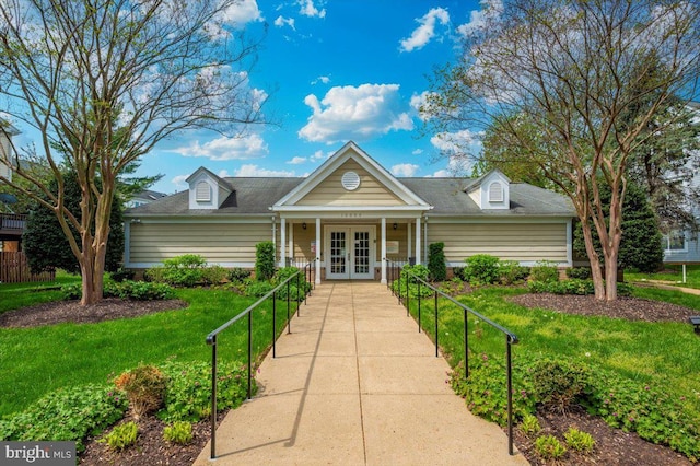 view of front of property featuring french doors, a front yard, and roof with shingles