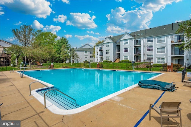 community pool with fence, a patio area, and a residential view