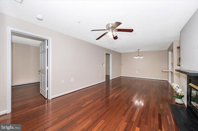 unfurnished living room featuring a glass covered fireplace, wood finished floors, baseboards, and ceiling fan with notable chandelier