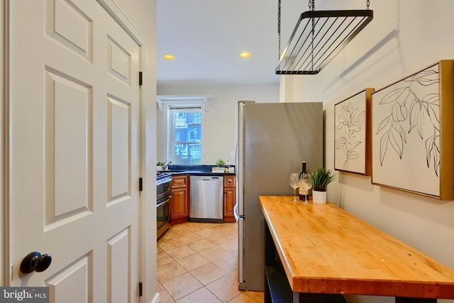 806 W 35th St, Baltimore, MD 21211 - kitchen featuring brown cabinets, wooden counters, light tile patterned floors, a sink, and appliances with stainless steel finishes