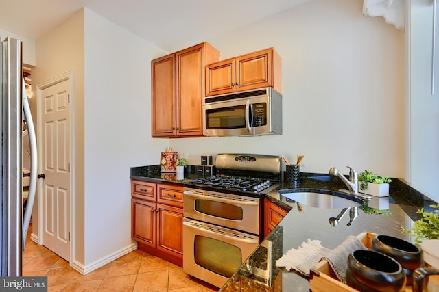 806 W 35th St, Baltimore, MD 21211 - kitchen featuring brown cabinets, dark stone countertops, appliances with stainless steel finishes, and a sink