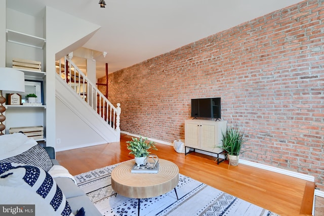 806 W 35th St, Baltimore, MD 21211 - living room with brick wall, baseboards, wood finished floors, and stairway