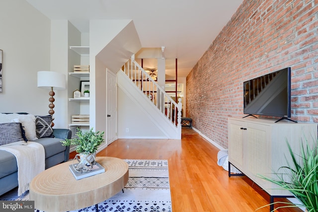 806 W 35th St, Baltimore, MD 21211 - living area featuring baseboards, built in shelves, brick wall, wood finished floors, and stairway