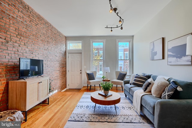 806 W 35th St, Baltimore, MD 21211 - living area featuring light wood finished floors, brick wall, baseboards, and rail lighting