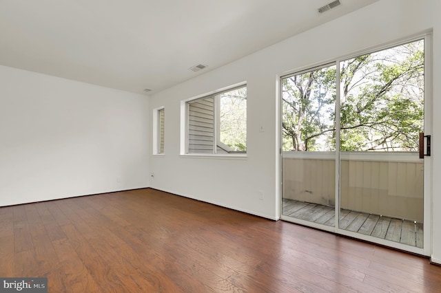 unfurnished room featuring visible vents, hardwood / wood-style floors, and baseboards