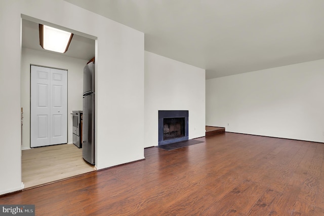 unfurnished living room featuring wood finished floors and a fireplace with flush hearth