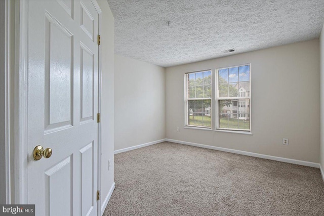 unfurnished room featuring carpet, a textured ceiling, visible vents, and baseboards