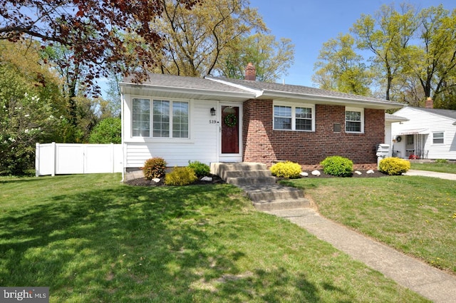 view of front of home with brick siding, a chimney, a front lawn, and fence
