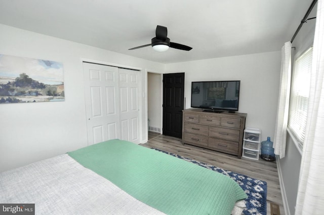 bedroom with baseboards, a ceiling fan, wood finished floors, and a closet