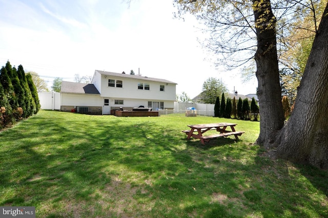 rear view of house featuring fence and a yard
