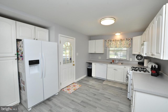 kitchen featuring a sink, light wood-style floors, white cabinetry, white appliances, and light countertops