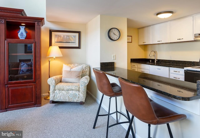 312 Severn Ave Unit W 401, Annapolis, MD 21403 - kitchen featuring dishwasher, range with electric cooktop, carpet flooring, white cabinets, and a kitchen bar