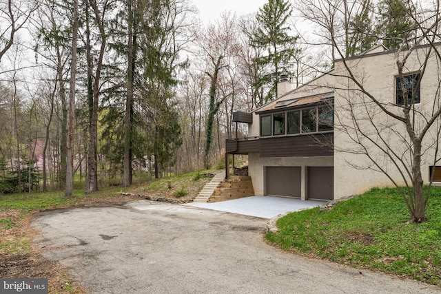 390 S Bryn Mawr Ave, Bryn Mawr, PA 19010 - exterior space with stucco siding, a chimney, driveway, stairs, and a garage
