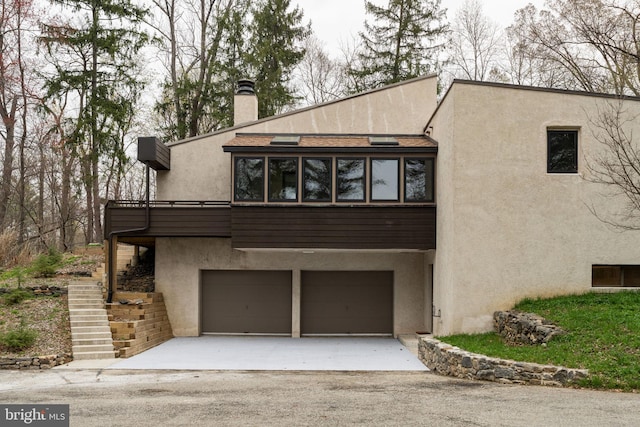 390 S Bryn Mawr Ave, Bryn Mawr, PA 19010 - exterior space featuring stucco siding, a chimney, stairway, aphalt driveway, and a garage
