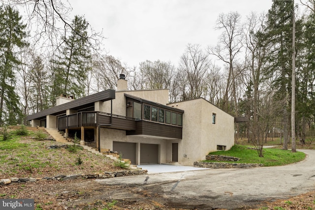 390 S Bryn Mawr Ave, Bryn Mawr, PA 19010 - view of side of home with a garage, a chimney, concrete driveway, stucco siding, and stairs