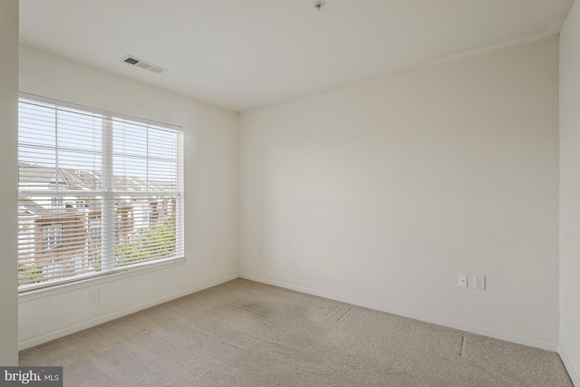 empty room with carpet floors, visible vents, and baseboards