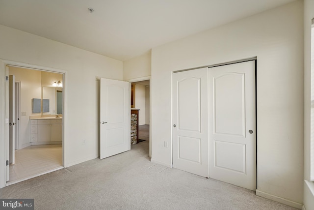 unfurnished bedroom with ensuite bath, baseboards, carpet floors, and a closet