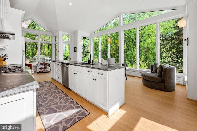 kitchen with white cabinets, dark countertops, vaulted ceiling, and a sink