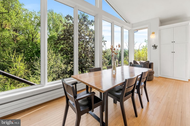 sunroom / solarium with wood-type flooring, vaulted ceiling, and a healthy amount of sunlight