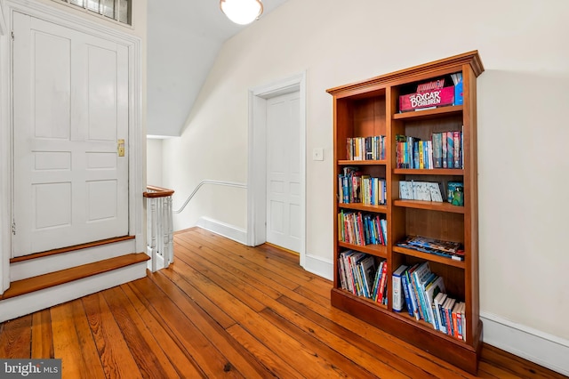 interior space featuring baseboards, hardwood / wood-style flooring, and lofted ceiling