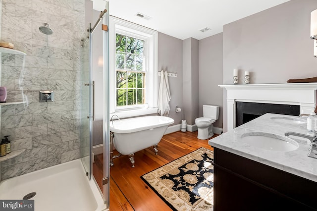 full bathroom with a stall shower, a freestanding bath, a sink, and wood finished floors