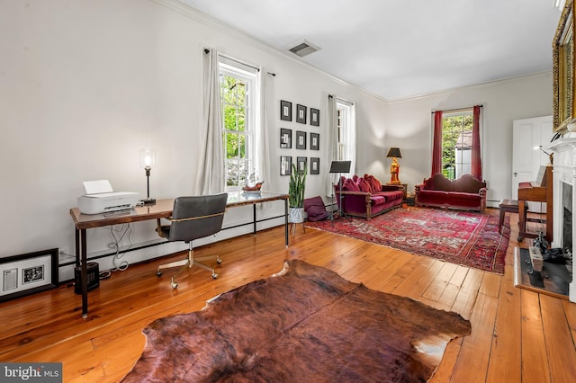 living room featuring visible vents, crown molding, hardwood / wood-style floors, and a fireplace