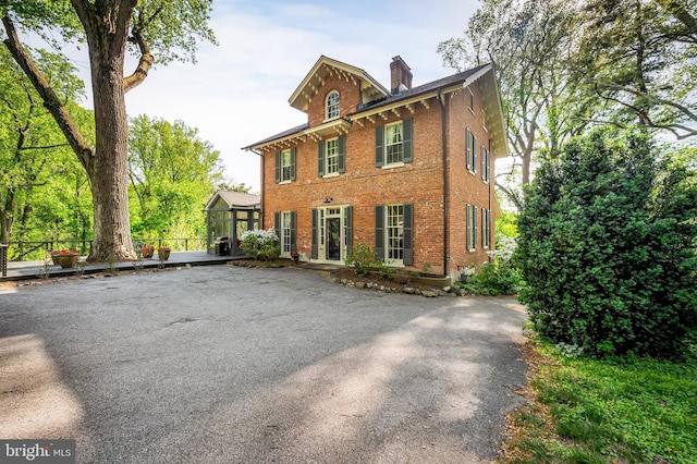 italianate-style house featuring fence, a chimney, and brick siding