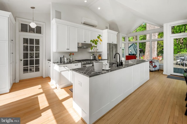 kitchen with a wealth of natural light, under cabinet range hood, white cabinetry, and an AC wall unit