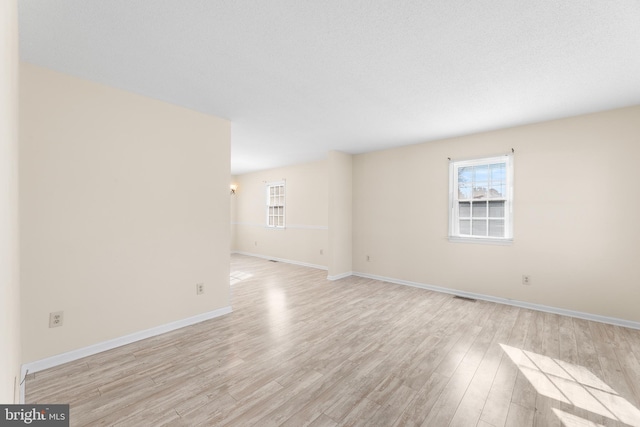 spare room with light wood-type flooring, baseboards, and visible vents