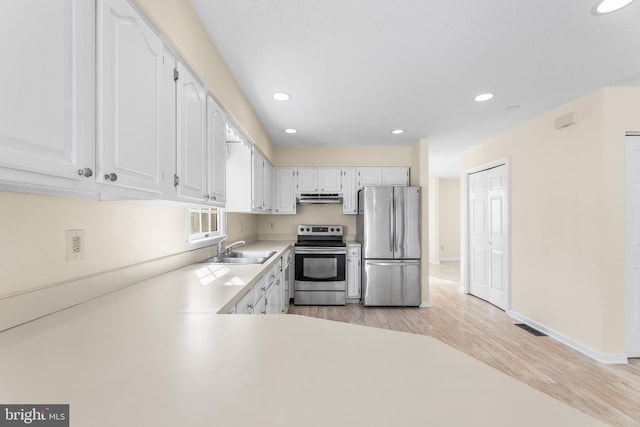 kitchen featuring light wood finished floors, a sink, recessed lighting, and stainless steel appliances