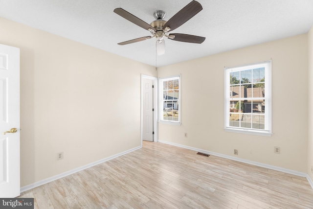 unfurnished room featuring light wood finished floors, baseboards, a ceiling fan, and visible vents