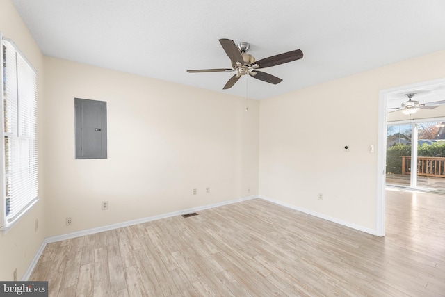 spare room featuring visible vents, light wood-type flooring, a ceiling fan, and electric panel