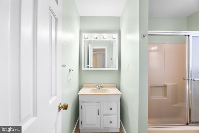 bathroom with vanity, baseboards, and a stall shower