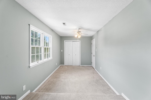 unfurnished bedroom with carpet, a textured ceiling, a closet, visible vents, and baseboards