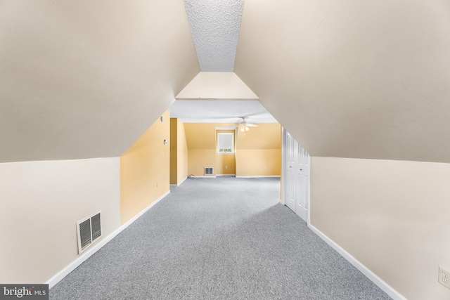 additional living space with baseboards, lofted ceiling, a ceiling fan, and visible vents