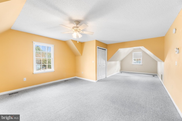 additional living space featuring a textured ceiling, ceiling fan, visible vents, and carpet floors