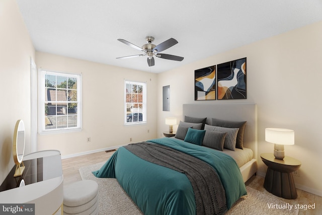 bedroom featuring wood finished floors, ceiling fan, baseboards, and electric panel