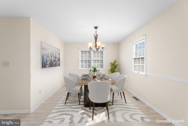 dining room with a chandelier, wood finished floors, baseboards, and visible vents