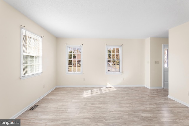 unfurnished room featuring visible vents, baseboards, and light wood finished floors