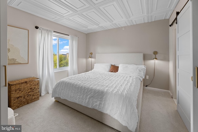 bedroom with light colored carpet, baseboards, an ornate ceiling, and a barn door