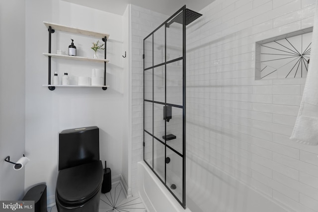 bathroom featuring toilet, baseboards, and shower / bath combination with glass door