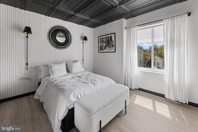 bedroom with light wood finished floors, baseboards, and an ornate ceiling
