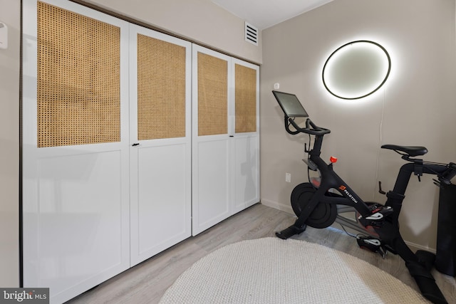 exercise room with visible vents, light wood-style flooring, and baseboards